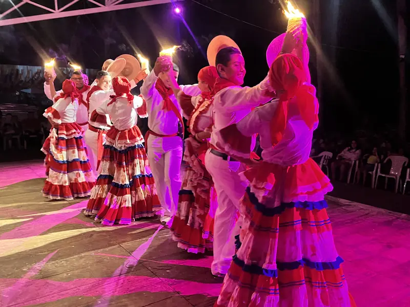 A large group on stage with candles at the festival.