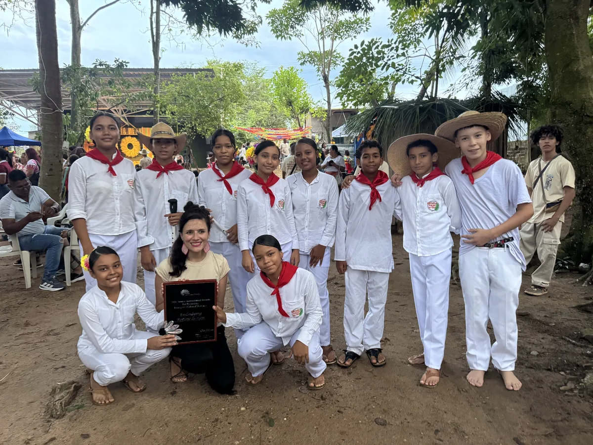 Children in white with red scarves and the JIAPICH award.
